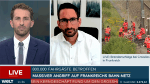 Corporate Resilience Management – 3-core 19 A news broadcast shows two male anchors discussing security concepts and crisis management, with an image of workers in orange suits responding to a rail incident onscreen. Headline: Massiver Angriff auf Frankreichs Bahn-Netz. Scrolling ticker and live labels are visible.