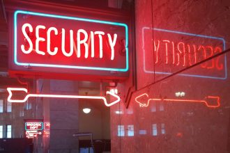 A red neon SECURITY sign with an arrow points right, reflected on a marble wall. In the background, a smaller neon BAGGAGE DEPT sign is visible.